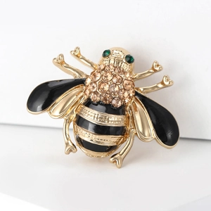 Macro view of bee brooch featuring gold metal wings with black enamel and champagne rhinestones