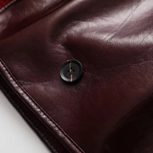 Macro shot of faux leather texture and a black four-hole button on the warm jacket