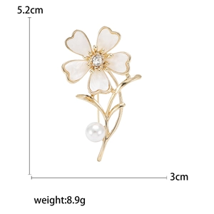 Elegant gold flower brooch with white enamel petals, rhinestone, and pearl detailing