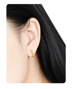 Macro shot of elegant gold-plated hoop earring with micro-pave white cubic zirconia stones