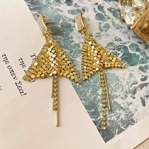 Detail of golden fringe earrings featuring sparkling rhinestones and triangular metal mesh