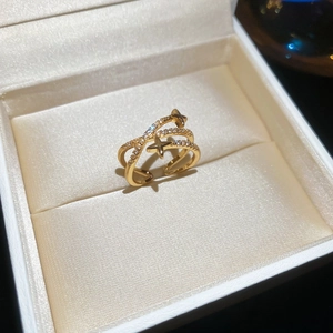 Detailed view of a gold plated crisscross star ring with tiny crystals in a jewelry box