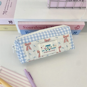Detail of blue plaid pencil case with happy label, floral patch, and sturdy white zipper