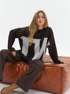 Detailed view of oversized brown knit sweater with large gray TM letter jacquard pattern