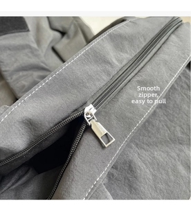 Detail of smooth silver metal zipper on durable dark grey nylon fabric bag