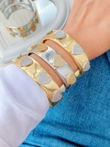 Close-up of gold and silver open bracelets with pavé heart charms on a female model