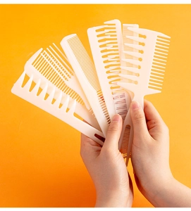 Detailed view of eight-piece white plastic hair comb set held for professional styling