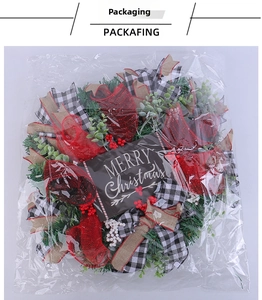 Detailed view of Merry Christmas wreath with ribbons and berries in transparent packaging