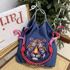 Close-up of vibrant tiger head embroidery on a navy nylon tote bag with colorful straps