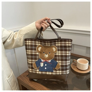 Detail of checkered tote bag featuring a cute teddy bear embroidery and brown leather straps