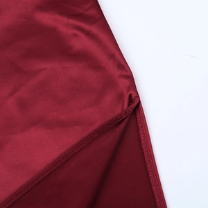 Detailed macro view of burgundy satin dress showing side slit and professional hem stitching