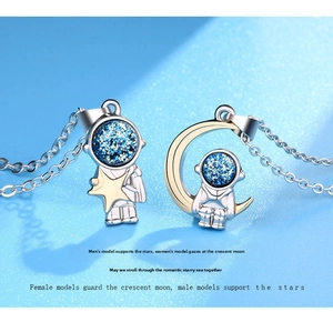 Close-up of astronaut couple necklaces featuring a star and moon pendant in silver and blue