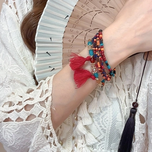 Detail of bohemian multilayer beaded bracelet with red tassels and colorful crystal beads