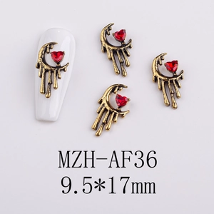 Macro shot of gold alloy nail art charm with red heart crystal and crescent moon details