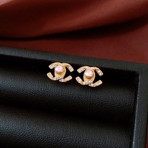 Detailed view of 14k gold-plated pearl earrings with CC logo on black leather box