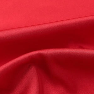 Detailed close-up of vibrant red satin fabric showing silky texture and elegant drapes