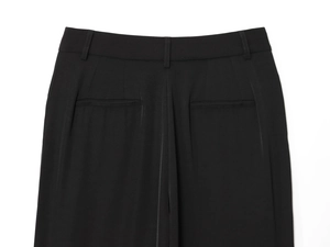 Detail of black straight-leg trousers showing back pockets and fine stitching craftsmanship