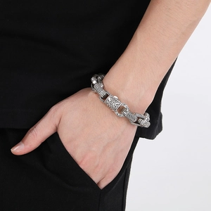 Macro view of vintage engraved floral patterns on a silver stainless steel men's bracelet