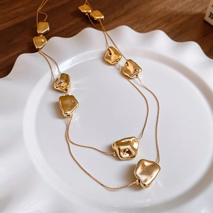 Dettaglio della collana a doppio strato con perle dorate su piatto in ceramica