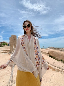 Detail of beige summer shawl featuring delicate colorful floral embroidery on lightweight fabric