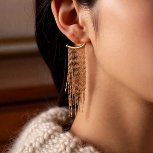 Close-up of elegant gold long tassel earrings worn by a model in soft lighting
