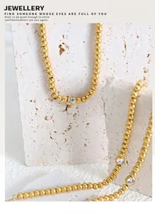 Close-up of gold-plated beaded necklace with circular clear zircon pendant on stone