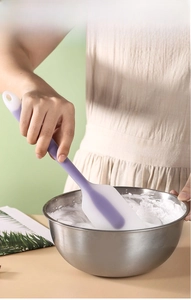 Silicone spatula mixing cream in a stainless steel bowl for baking cakes
