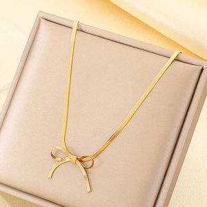 Détail du collier avec pendentif nœud plaqué or 18 carats sur un coffret à bijoux texturé