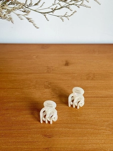 Macro detail of two cream white acetate hair claws featuring France Handmade engraving