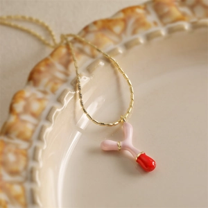 Collier doré avec pendentif émaillé rose et rouge sur assiette en céramique