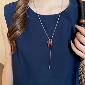 Minimalist Y-shaped necklace with a red Dala horse pendant and star design on a long silver chain