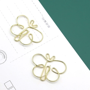 Elegant butterfly shaped gold metal paper clips shown on a minimalist white envelope