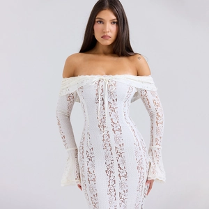 Dettaglio dell'elegante abito lungo in pizzo bianco con spalle scoperte e maniche lunghe