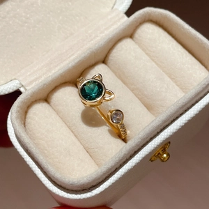 Close-up of a cat-ear ring with green and white zircons in a jewelry box
