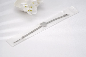 Dettaglio del bracciale a maglia argento con ciondolo a cuore e chiusura a moschettone