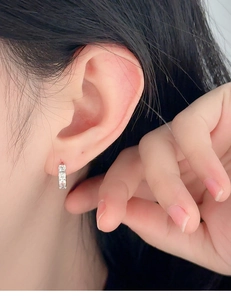 Detailed close-up of a silver hoop earring set with sparkling cubic zirconia on an ear