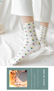 Detail of white cotton crew socks with cable knit texture and small floral patterns