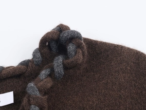 Gros plan détaillé du cardigan en maille marron avec bordure tressée et texture laine