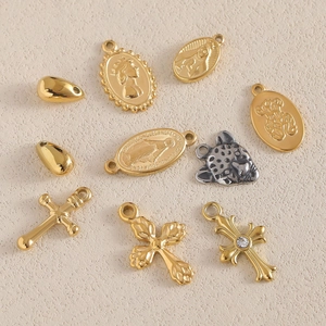 Flat lay of assorted 18K gold and silver charms including crosses and animal motifs