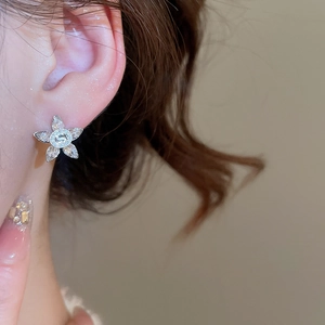 Close-up of sparkling zircon flower earrings with a silver-tone finish on ear