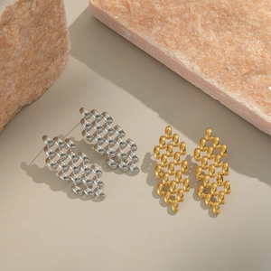 Boucles d'oreilles tissées dorées et argentées présentées sur des pierres naturelles