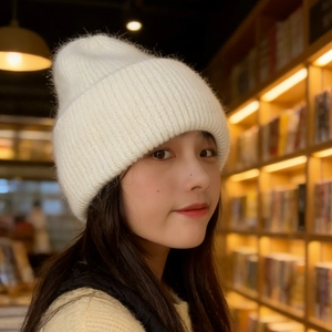 Close-up of white knitted beanie showing soft rabbit fur texture and thick ear protection