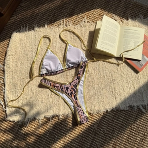 Detail view of leopard print bikini with metallic gold trim on a textured jute background