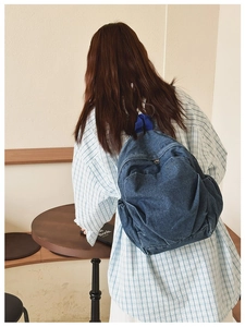 Close-up of a blue denim backpack with dark blue top handle in a cozy cafe setting