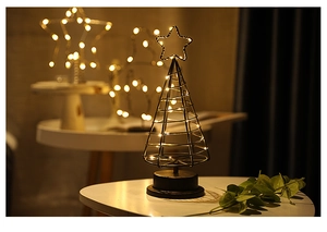 Close-up of metal wire Christmas tree lamp with warm white LED string lights on black base