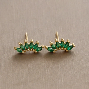 Macro shot of fan-shaped stud earrings with marquise green stone and 18K gold plating