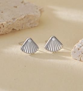 Macro detail of silver S925 seashell stud earrings with realistic textured finish