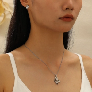 Close-up of model wearing silver M LOVE M necklace and stud earrings jewelry set