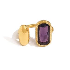 Détail macro d'une bague dorée ouverte asymétrique avec pierre violette et bille dorée