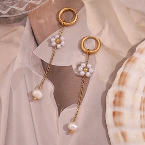 Detail of 18K gold plated hoop earrings with handmade pearl flowers on silk fabric